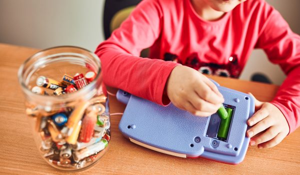Kind die gebruikte batterijen in een pot doet