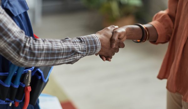 Twee mensen die de hand schudden, een heeft gereedschap om zijn middel